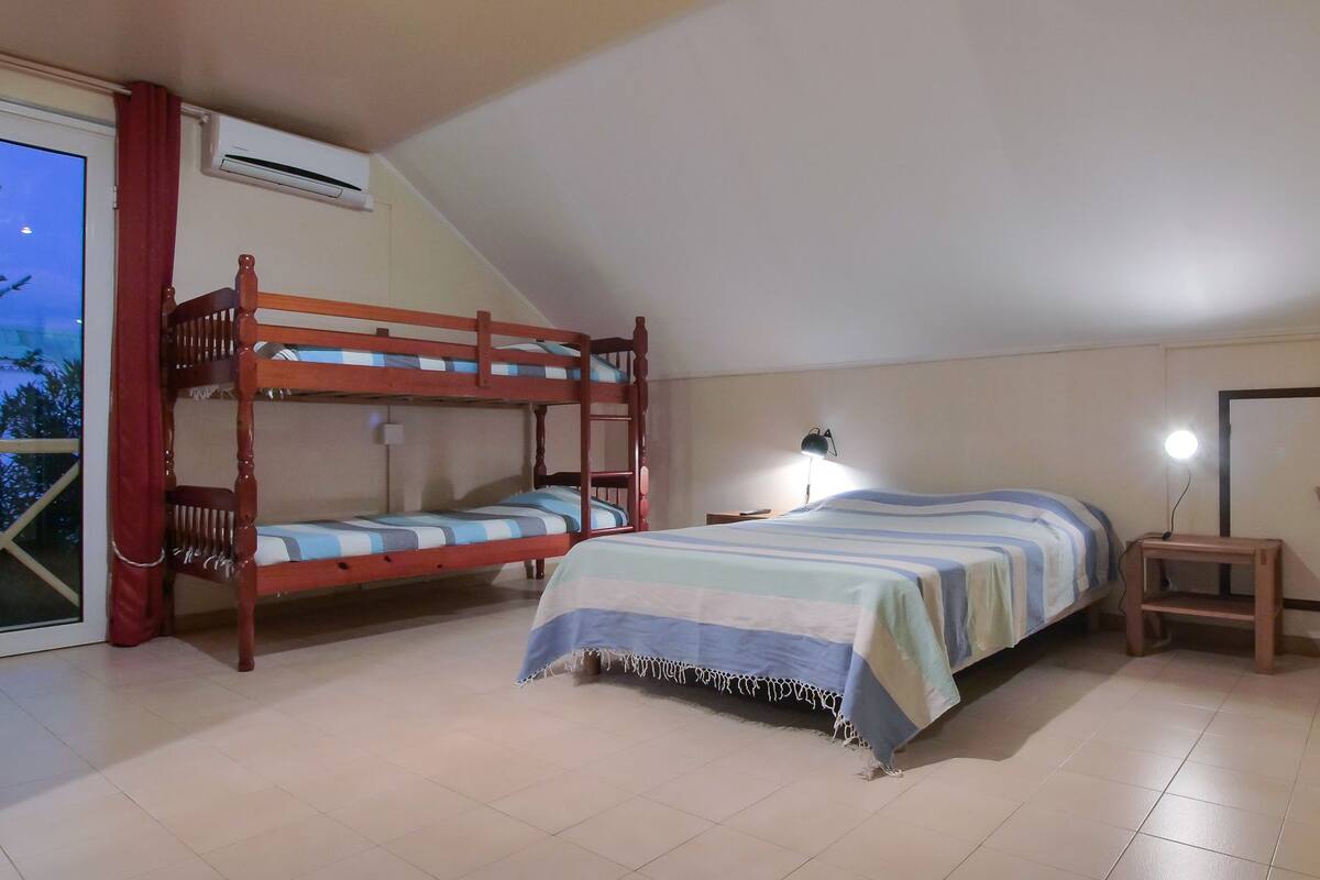 Un dormitorio con literas, un escritorio, una silla, una lámpara y un armario.