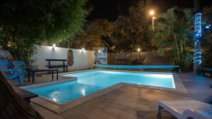 Una piscina al aire libre, sombrillas, sillones reclinables de piscina