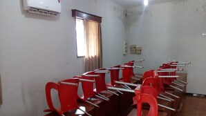 A conference room with rows of red chairs and a long table.