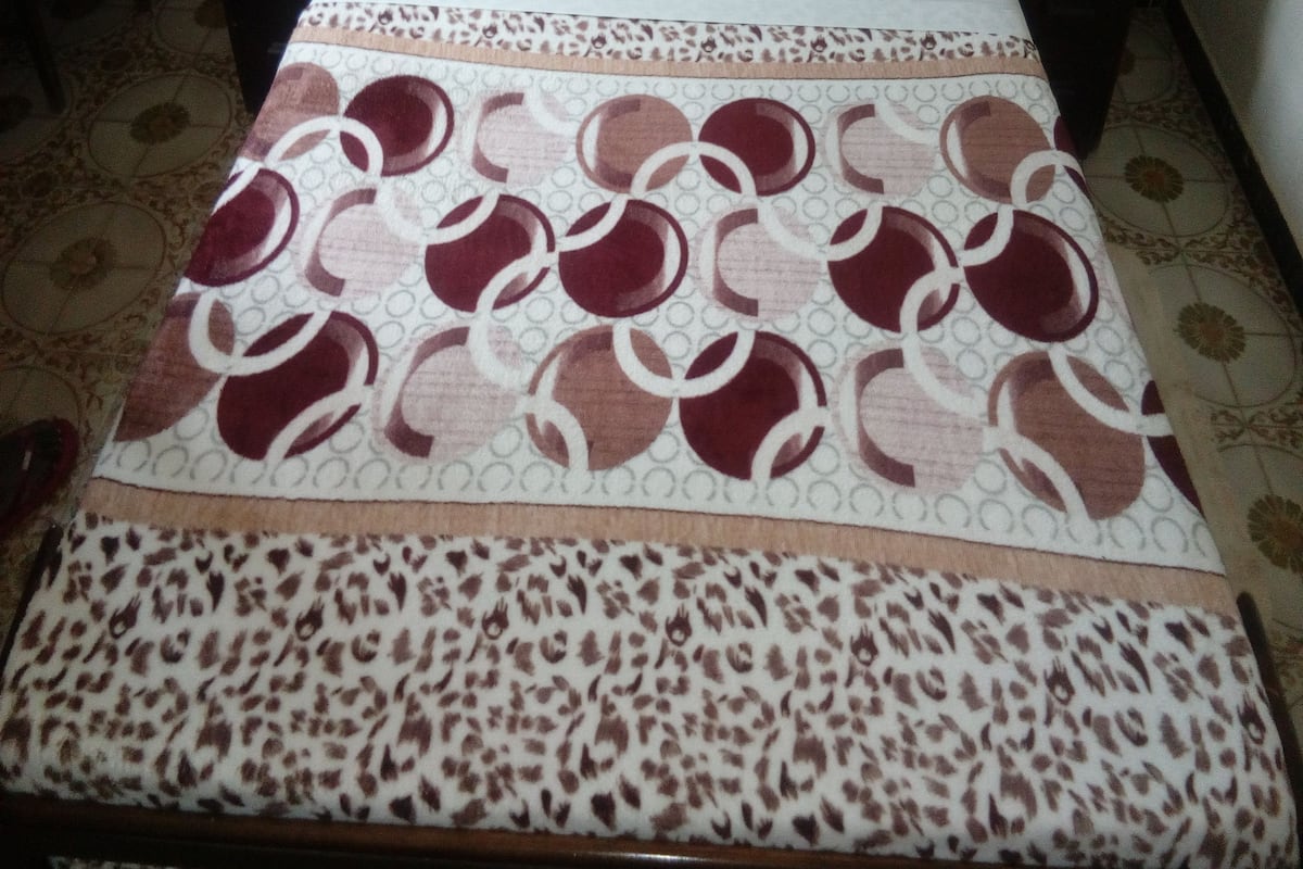 A bed with a patterned bedspread, two pillows, and a wooden headboard.