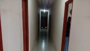 A corridor with tiled flooring and wooden doors on either side.