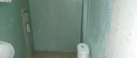 Ein kleines Badezimmer mit Toilette, Waschbecken und einem blauen Toilettenpapierhalter.