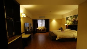 A hotel room with a bed, a desk, a chair, a sofa, and a large panda painting on the wall. - Panda Prince Hotel Hongpailou Branch (Chengdu)