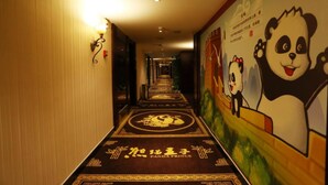 A hallway with a panda-themed mural on the right wall, a patterned carpet, and a light fixture on the left. - Panda Prince Hotel Hongpailou Branch (Chengdu)