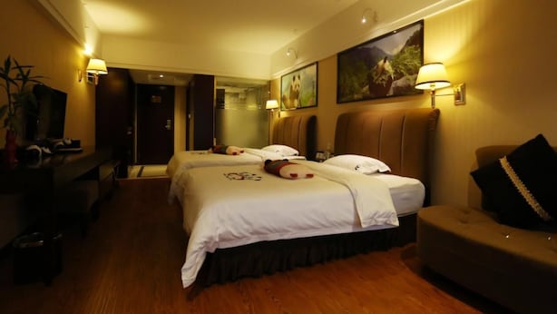 A hotel room with two beds, a sofa, a TV, and wall-mounted lamps. - Panda Prince Hotel Hongpailou Branch (Chengdu)