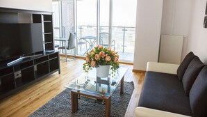 Een woonkamer met een televisie, bank, salontafel en balkon met uitzicht.