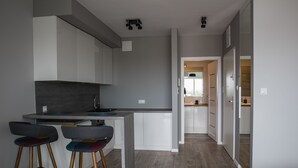 Een moderne keuken met witte kasten, een centraal kookeiland en twee barkrukken.