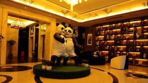 Eine Lobby mit einer Panda-Statue, einem Empfangstresen und Regalen mit verschiedenen Artikeln.