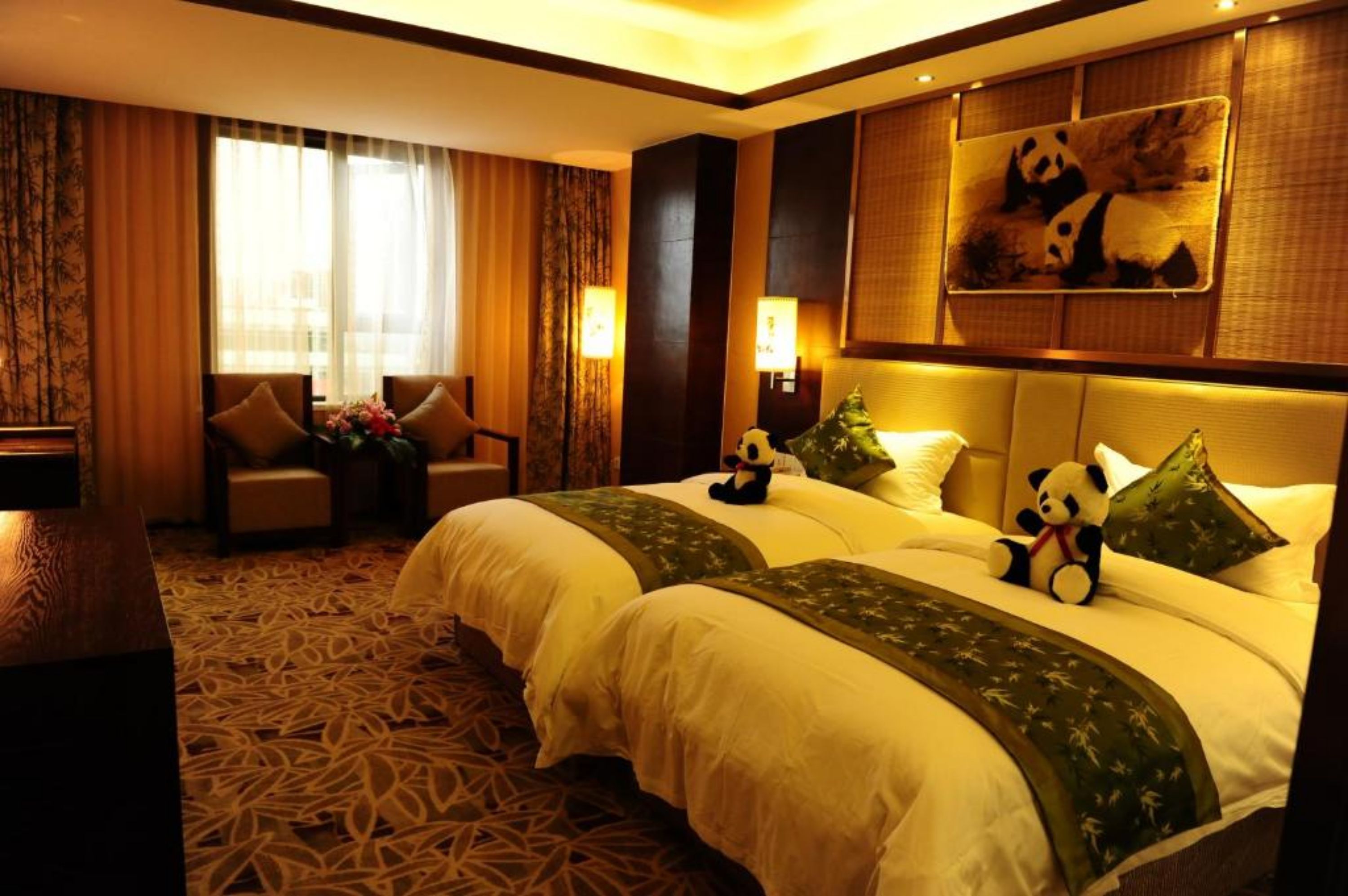 A hotel room with two beds, a sofa, a desk, and a large panda-themed artwork on the wall.