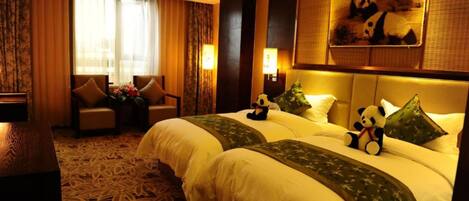 A hotel room with two beds, a sofa, a desk, and a large panda-themed artwork on the wall.