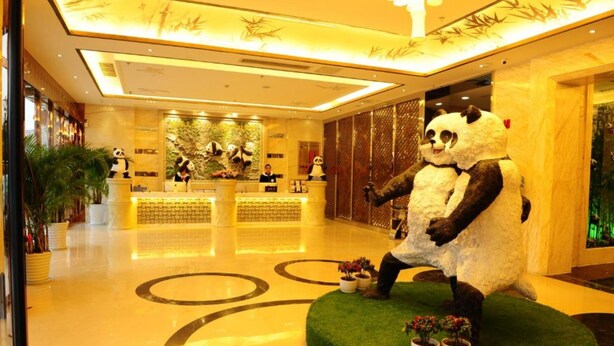 Eine Lobby mit einer Rezeption, Panda-Statuen und einem polierten Boden mit kreisförmigen Mustern.