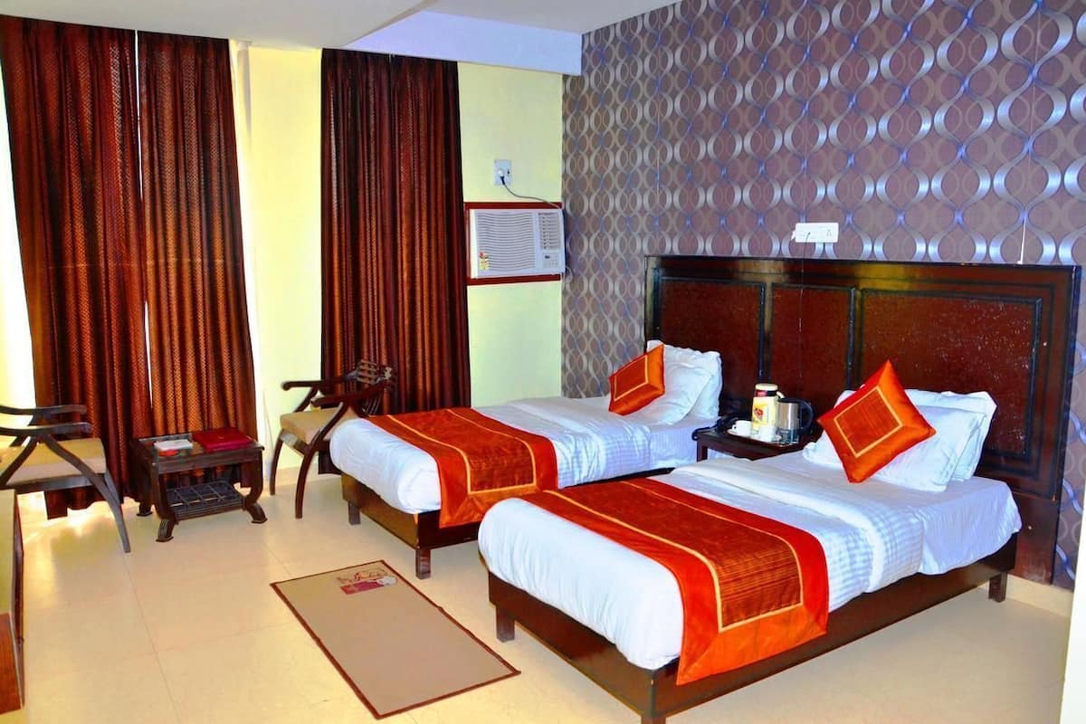 A hotel room with two beds, a desk, a chair, and a small table.