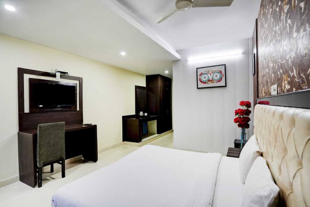 A hotel room with a bed, a desk, a TV, a wardrobe, and a painting on the wall.