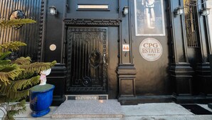 Una reja de metal negro con un pomo decorativo, una placa sobre la puerta y un cartel que indica 'CPG ESTATE 2015'.