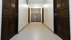 A hallway with two dark wooden doors on either side, a tiled floor, and a light-colored wall. - RedDoorz near NAIA Terminal 1 (Parañaque)