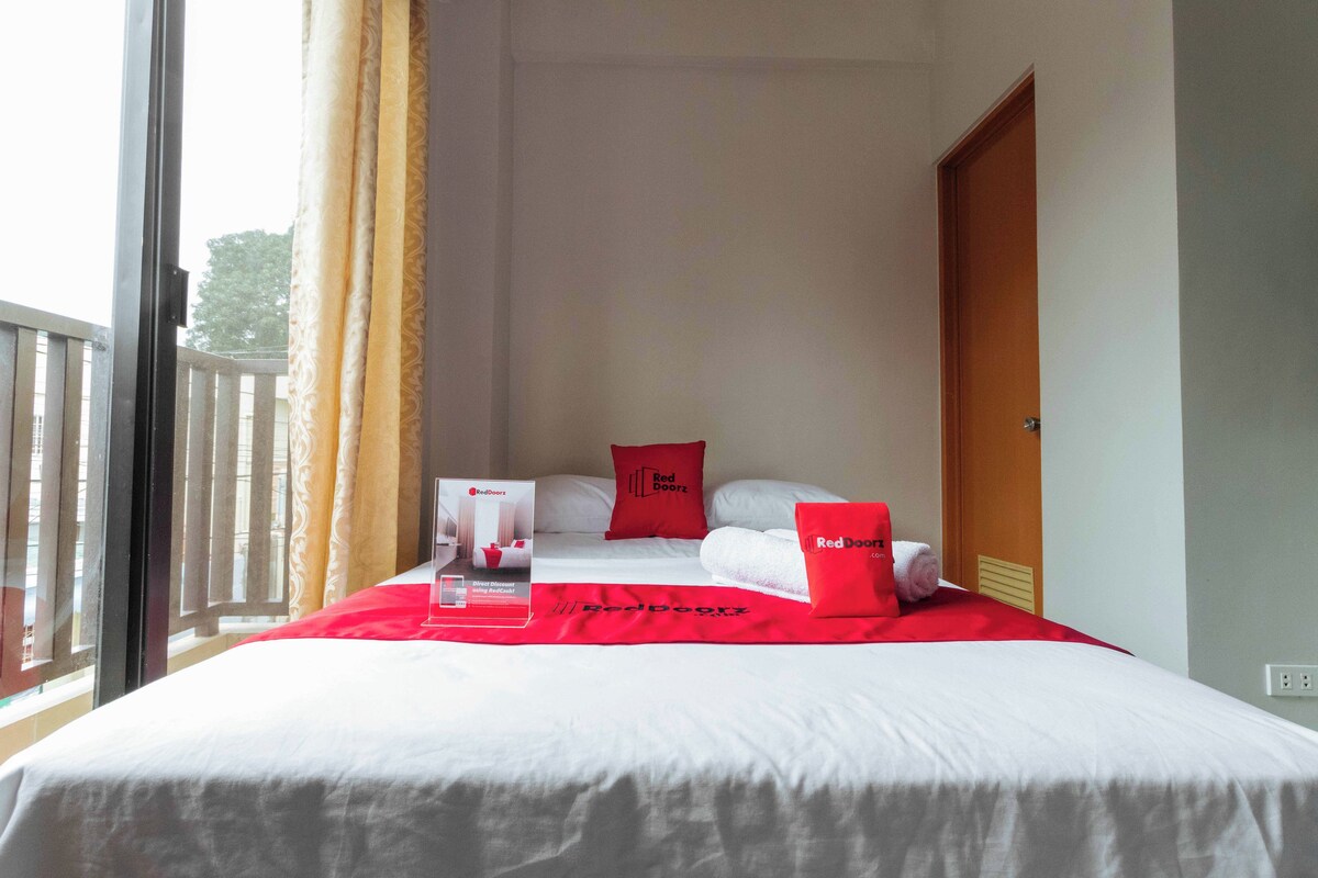 Una camera d'albergo con un letto, cuscini rossi, una coperta rossa e il cartello di RedDoor.
