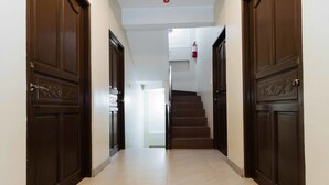 A hallway with dark wooden doors, a staircase, and a white wall. - RedDoorz near NAIA Terminal 1 (Parañaque)