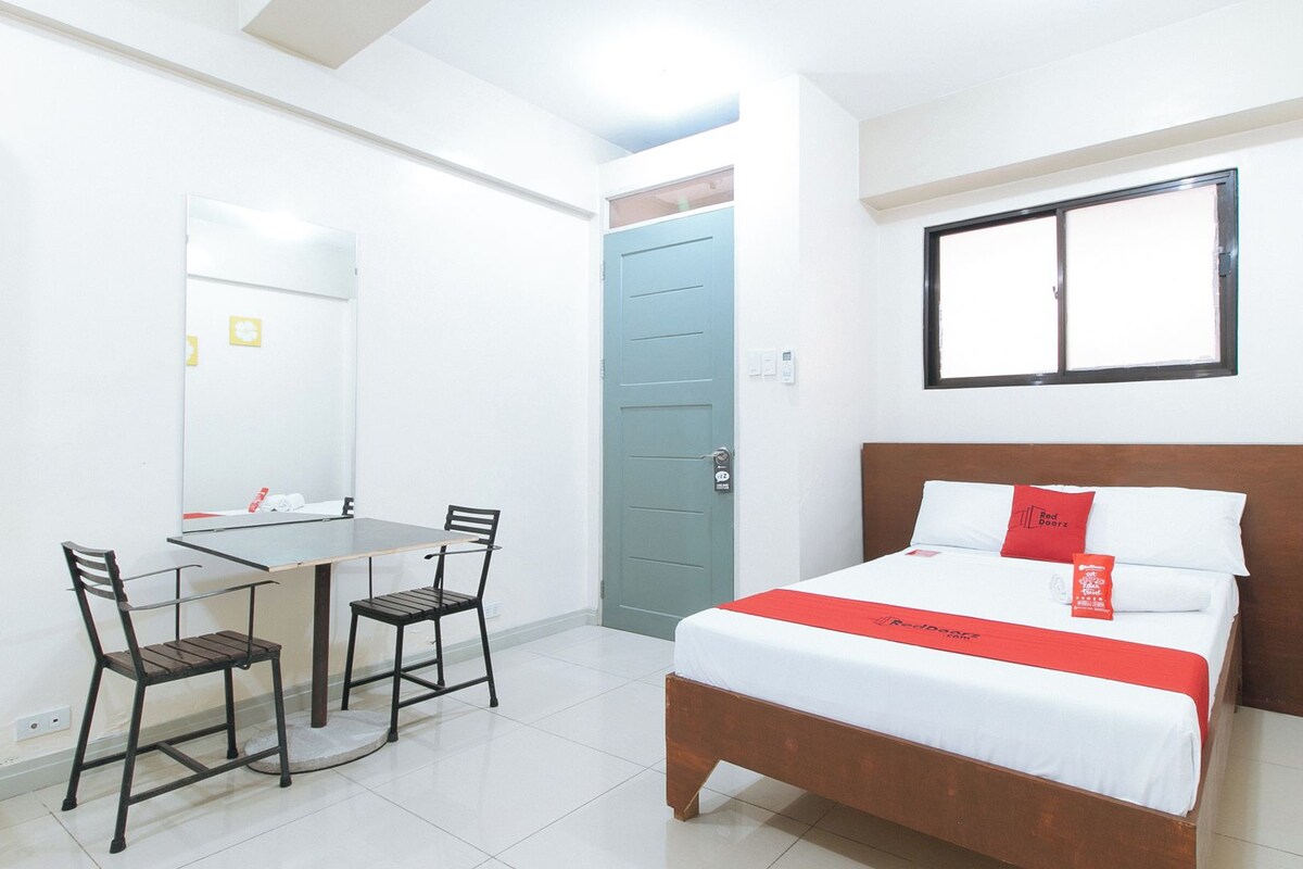 A hotel room with a bed, a desk, and two chairs.