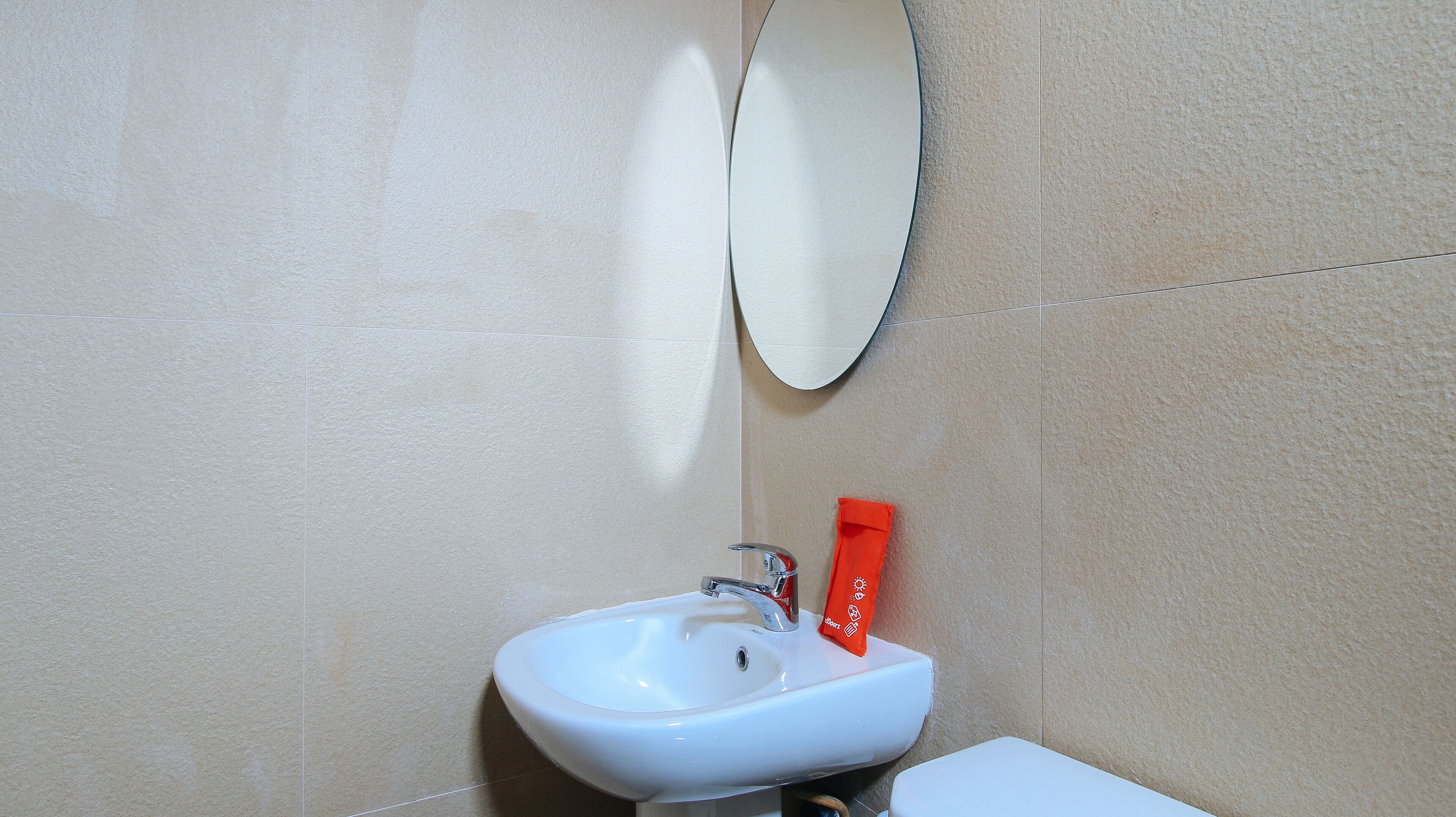 A bathroom with a white sink, a mirror, and a red towel hanging on the wall.