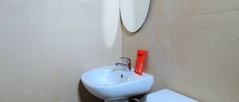 A bathroom with a white sink, a mirror, and a red towel hanging on the wall.
