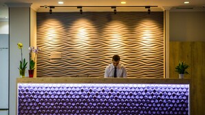 Mostrador de recepción con pared de textura ondulada y un panel de luz hexagonal.