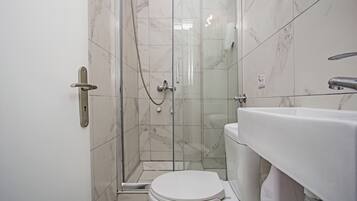 Une salle de bain avec une douche à parois de verre, des toilettes et un lavabo.