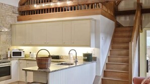 Eine Küche mit weißen Schränken, einer Granit Arbeitsplatte, einer Mikrowelle, einem Wasserkocher und einem Korb.