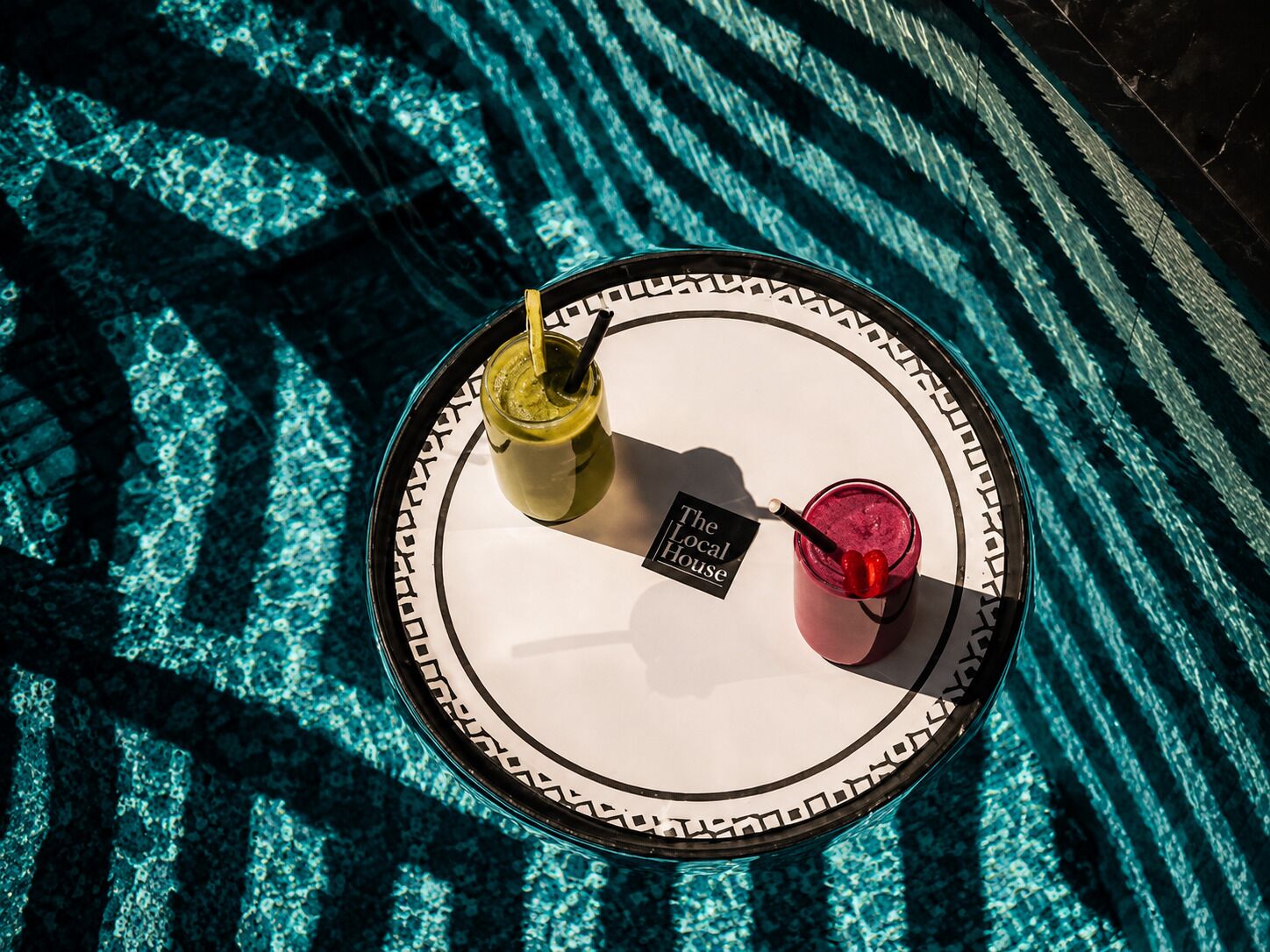 Un plateau avec deux boissons et un panneau posé sur une nappe à motifs.