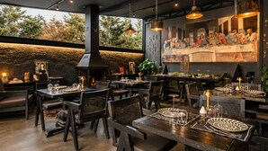 An indoor dining area with tables, chairs, and a large painting on the wall. - The Local House Alaçatı (Cesme)