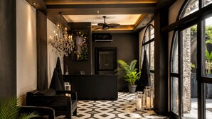 A reception area with a geometric patterned floor, a reception desk, a ceiling fan, and a large window offering a view outside. - The Local House Alaçatı (Cesme)