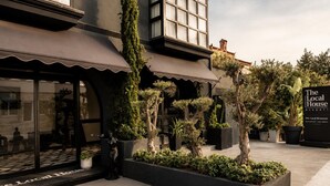 A building with a modern facade, outdoor seating area, and potted plants. - The Local House Alaçatı (Cesme)