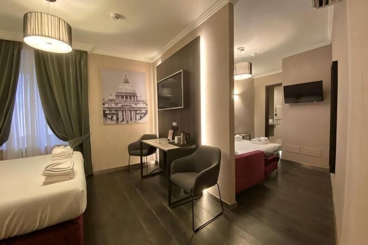 A hotel room with a bed, a desk, a chair, a TV, and a bathroom.