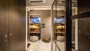 A modern hotel room with dark wood doors, a marble floor, a television on the wall, and a small seating area with a table and chairs. - PAX Hotel (Rome)