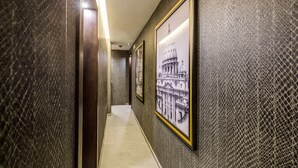 A hallway with textured walls and framed pictures of architectural landmarks. - PAX Hotel (Rome)
