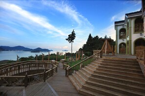 A wooden staircase leading to a building with a view of a body of water and mountains in the background.