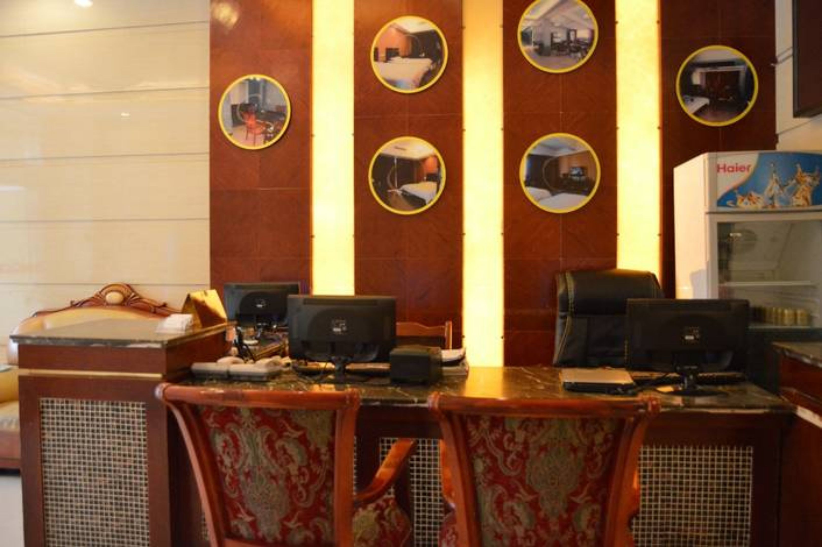 A hotel room with a dining area featuring a wooden table, chairs, and a refrigerator.