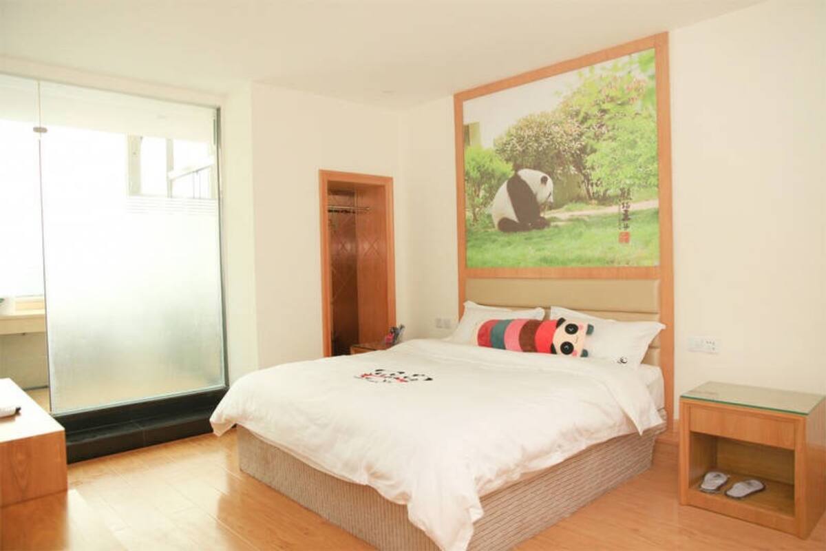 Une chambre à coucher comprenant un lit, une table de chevet en bois, une table en verre et une porte donnant sur un balcon.