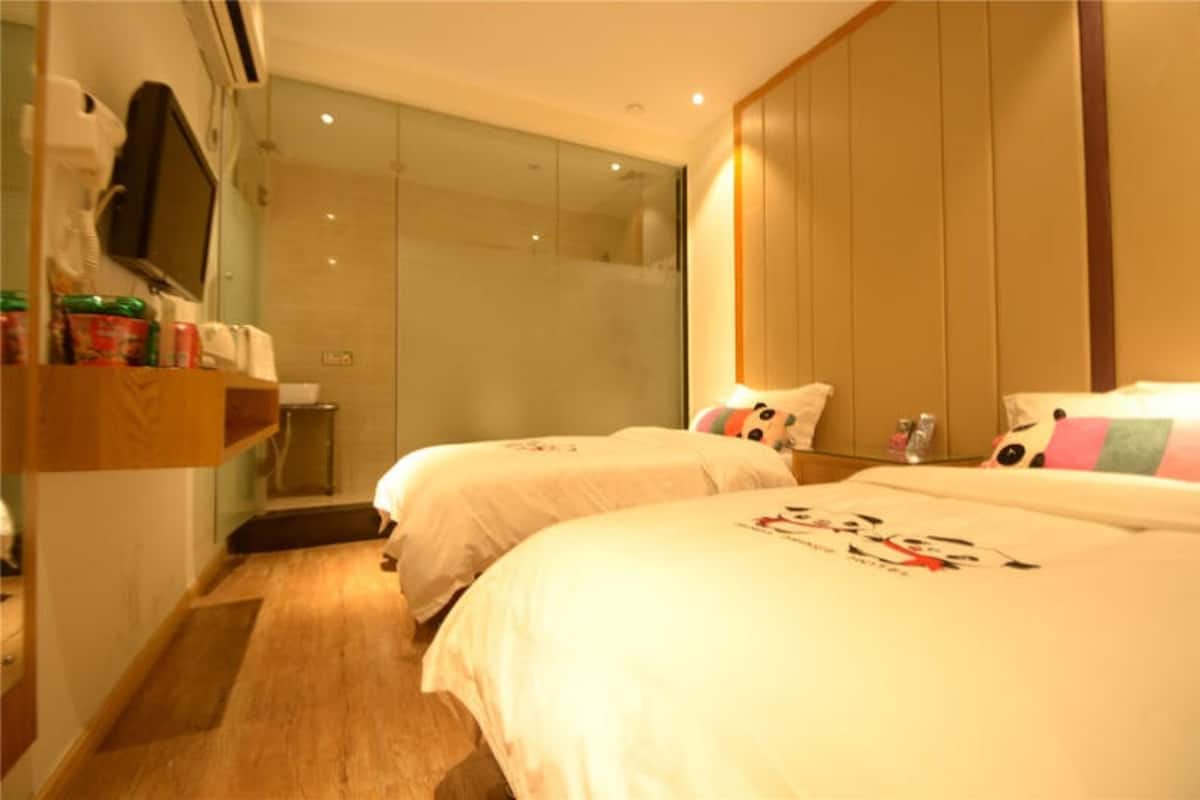 Une chambre d’hôtel avec deux lits, une armoire en bois, un miroir et une cabine de douche en verre.