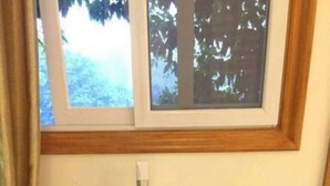 Uma mesa de madeira com um telefone, uma lâmpada, uma cafeteira e um controle remoto.
