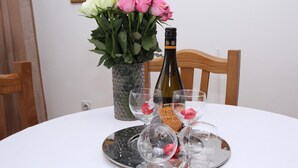 Une table à manger avec une bouteille de vin, des verres et un vase de fleurs.