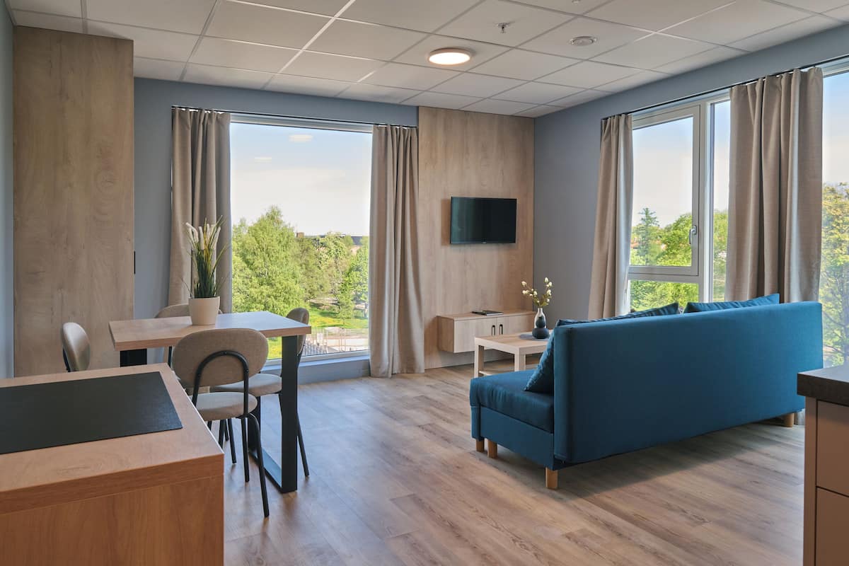 Een moderne hotelkamer met een zithoek, een bank en een aan de muur bevestigde televisie.