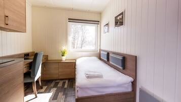 A compact bedroom with a bed, a desk, and a chair.