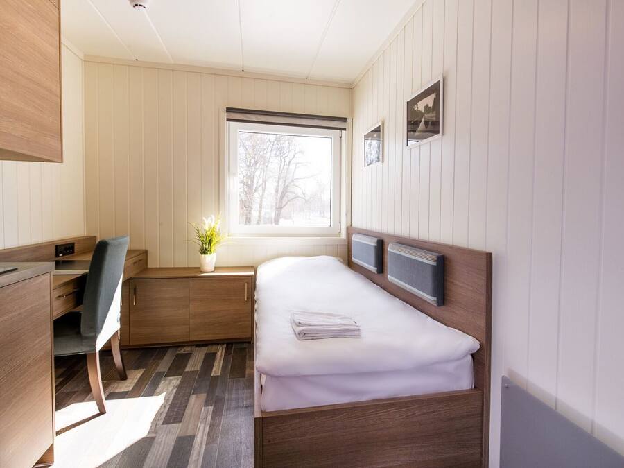 A compact bedroom with a bed, a desk, and a chair.