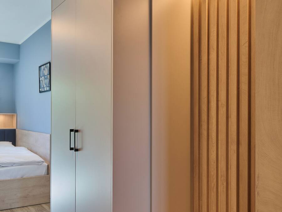 A modern bedroom with a large wardrobe, a bedside table, and a lamp.