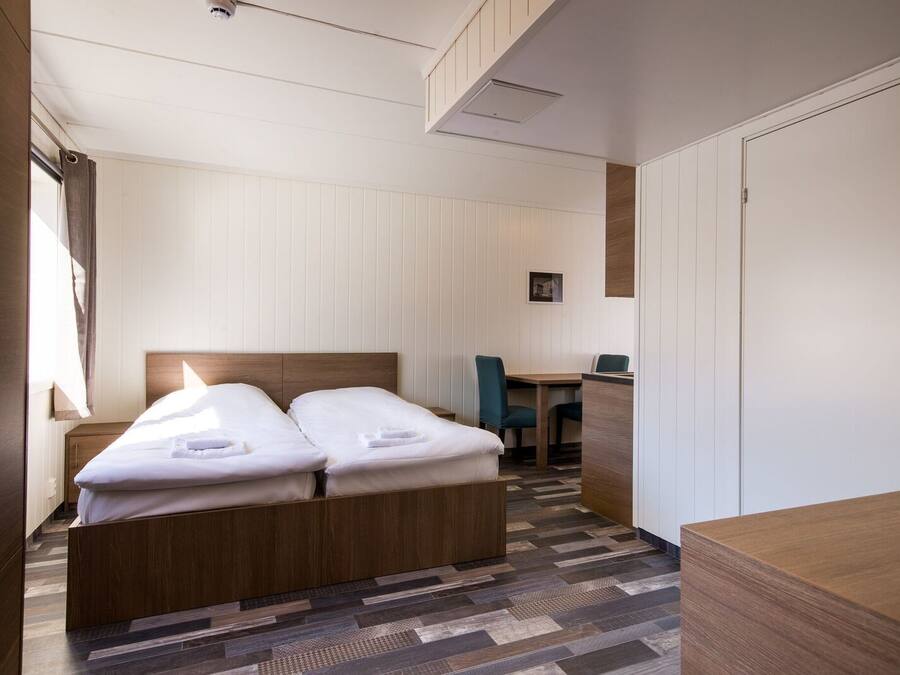 Een hotelkamer met een tweepersoonsbed, een bureau en een stoel.