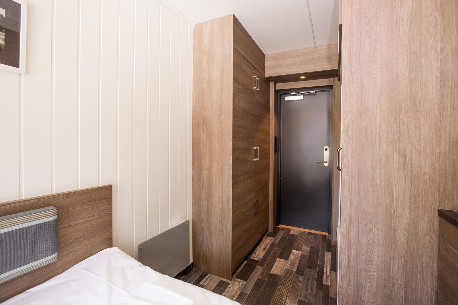 A hotel room with a bed, a wardrobe, and a door leading to another room.
