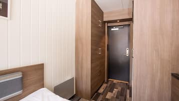 A hotel room with a bed, a wardrobe, and a door leading to another room.