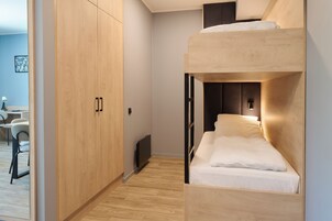 Dormitorio con literas, un armario de madera y un escritorio con silla.