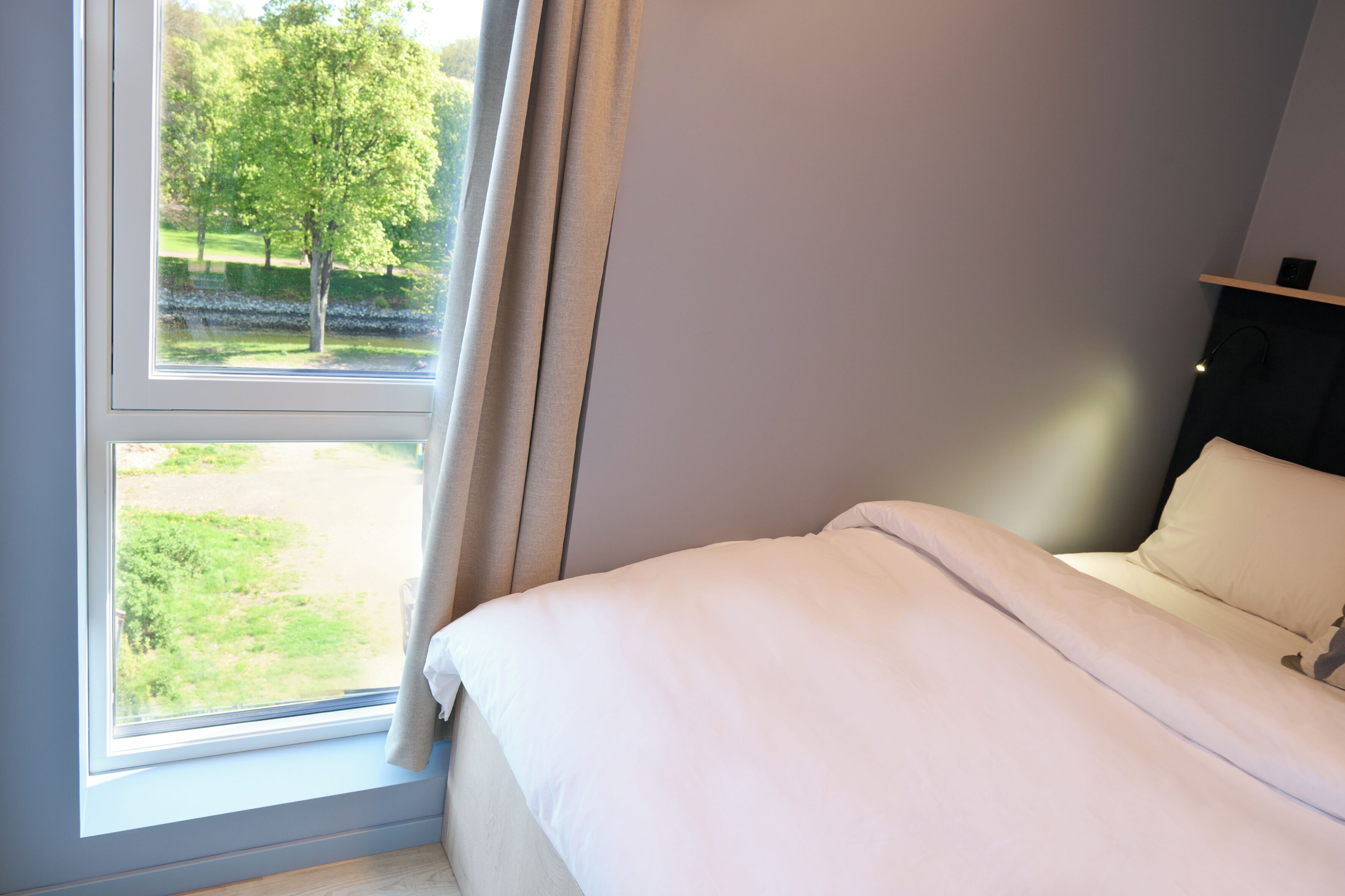 Ein Schlafzimmer mit Bett, Fenster und Parkblick.