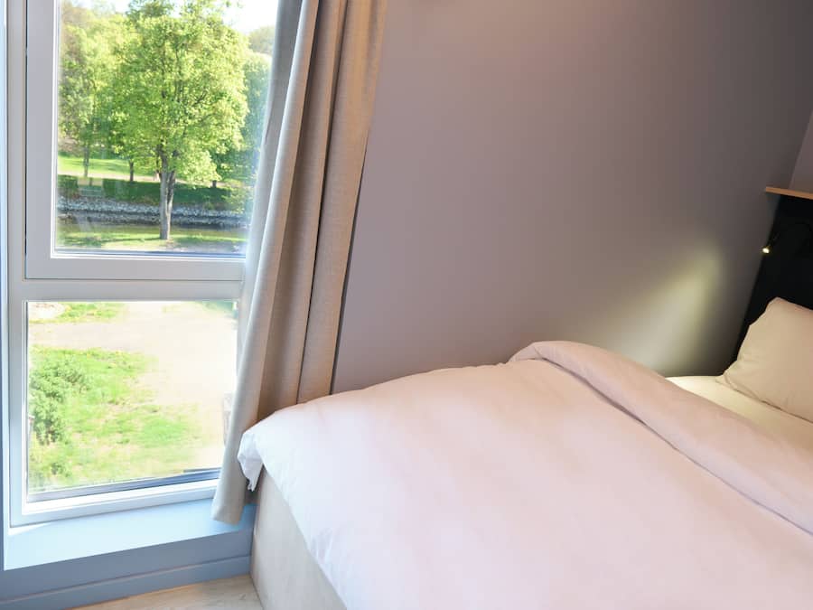 Ein Schlafzimmer mit Bett, Fenster und Parkblick.